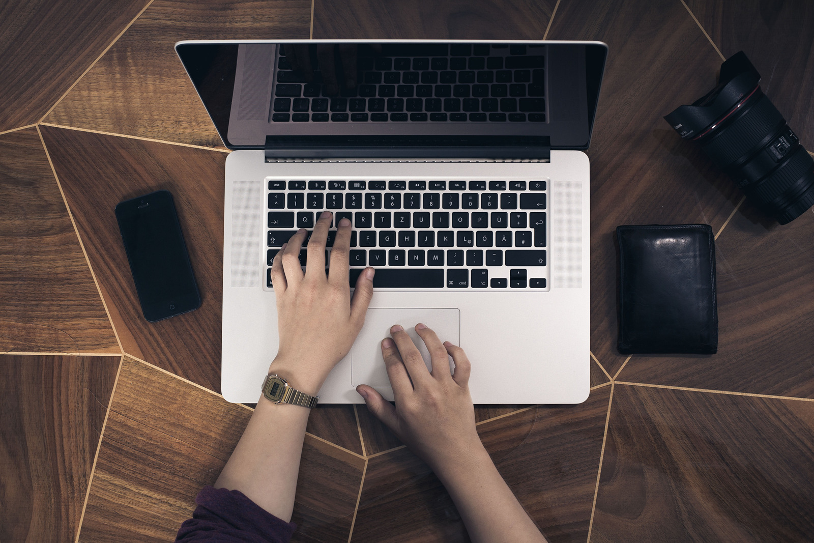 Hands working on a laptop at a timber desk